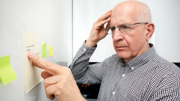 Älterer Mann mit Demenz, der Notizen betrachtet und versucht sich zu erinnern.