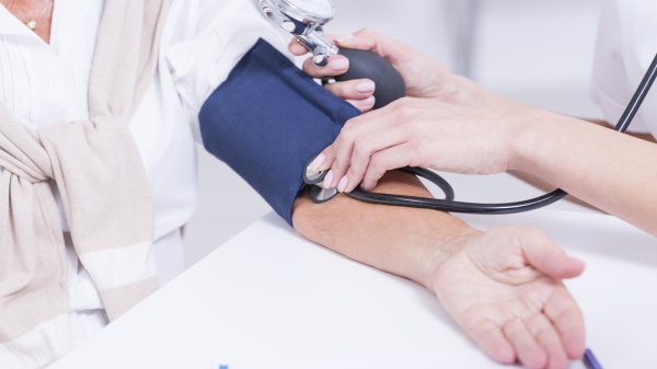 Blutdruckmessen bei einer Person mit Manschette und Stethoskop.