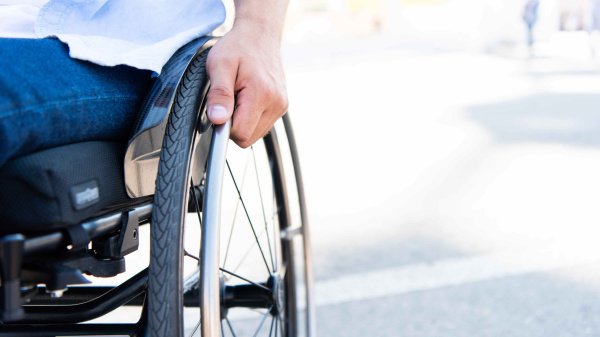 Person im Rollstuhl mit Fokus auf ein Rad.