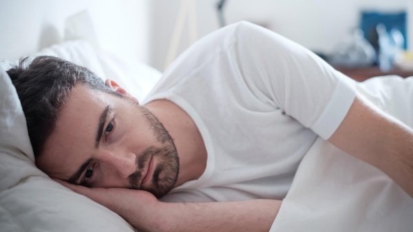 Ein Mann liegt nachdenklich im Bett. Die Anzeichen einer Depression sind vielfältig. Auch Schlafstörungen und ein pessimistischer Zukunftsblick sind Charakteristika für eine Depression.