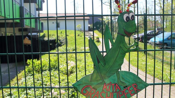 Ein gebastelter Grashüpfer ist befestigt am Zaun vor der Kita "Die Grashüpfer" in den Paracelsus Rehakliniken Bad Essen.