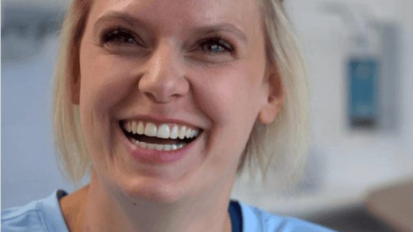 Portrait einer lachenden blonden jungen Patientin auf einem Klinikflur