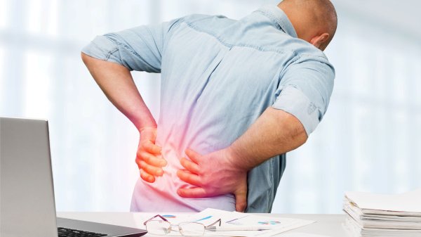 Darstellung eines sitzenden Mannes am Arbeitsplatz mit Rückenschmerzen im unteren Wirbelsäulenbereich durch Osteochondrose