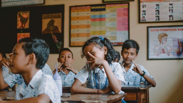 Schulkinder auf Bali im Klassenraum zeigen Peace-Zeichen.