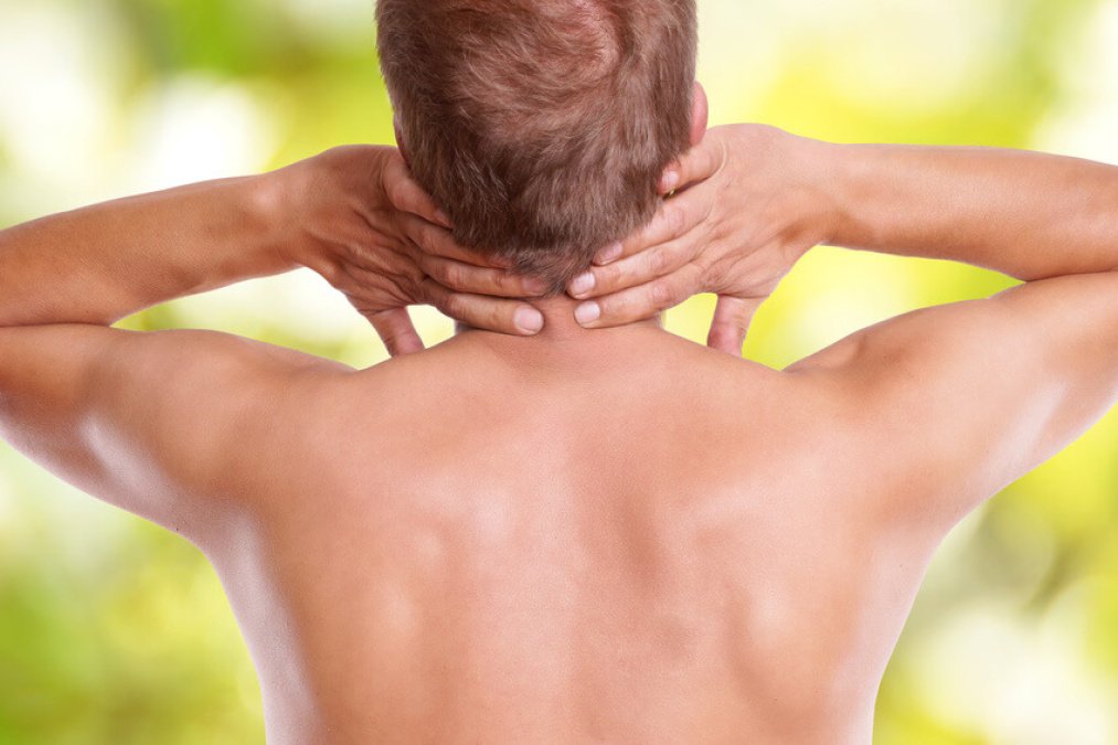Ein Mann hält seine beiden Hände in den Nacken aufgrund von Schmerzen in der Halswirbelsäule.