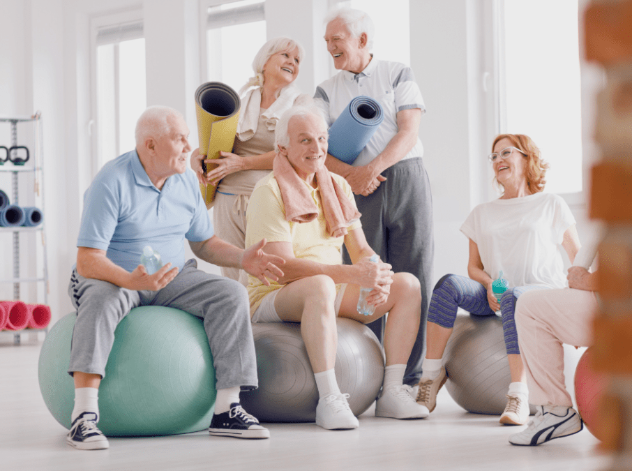 Gemischte Gruppe von Rehabilitanden im Training mit Gymnastikball und Matten