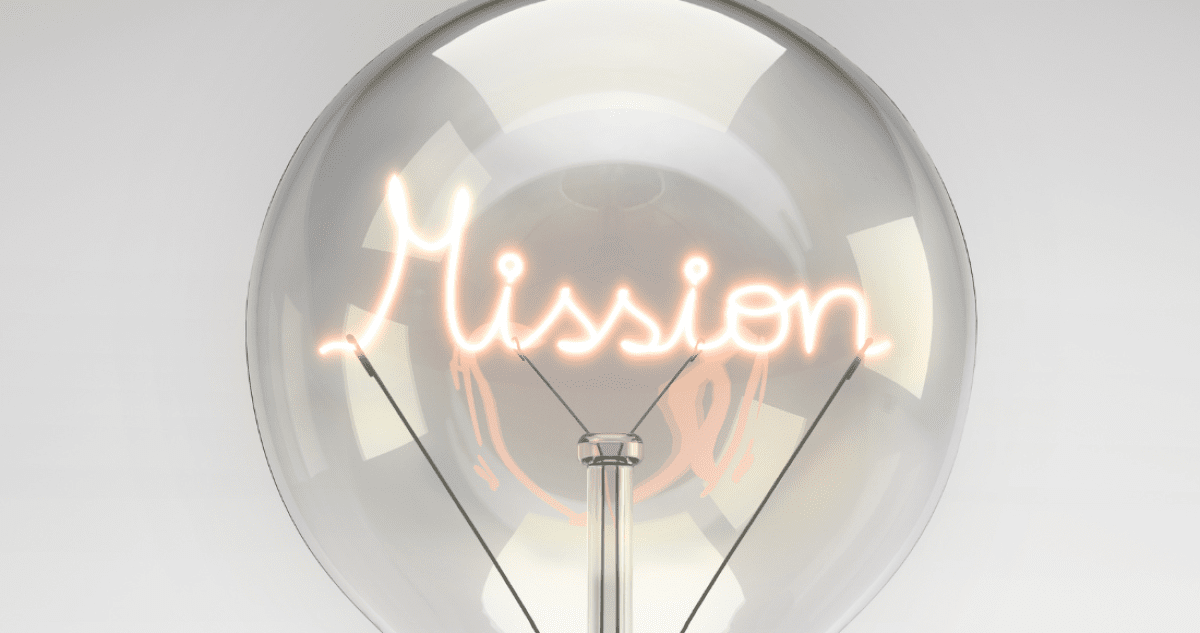 Graue Glühbirne mit leuchtendem Schriftzug "Mission" in hellem orange