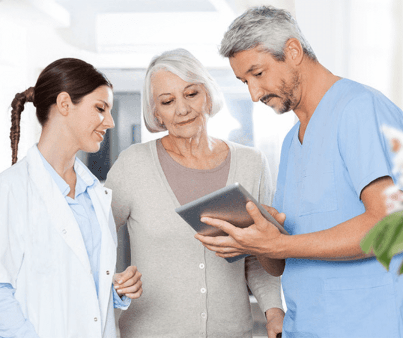 Ärztin im weissen Kittel, ältere Patientin und Arzt mit Tablet im blauen Kasak im Beratungsgespräch